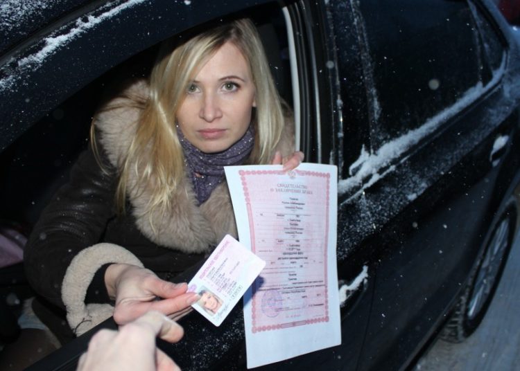 Девушка за рулем показывает права и страховку